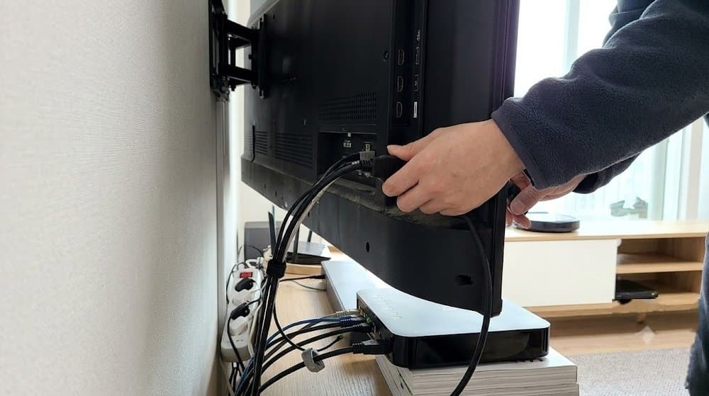 TV 뒷면 케이블과 셋톱박스를 점검하는 모습